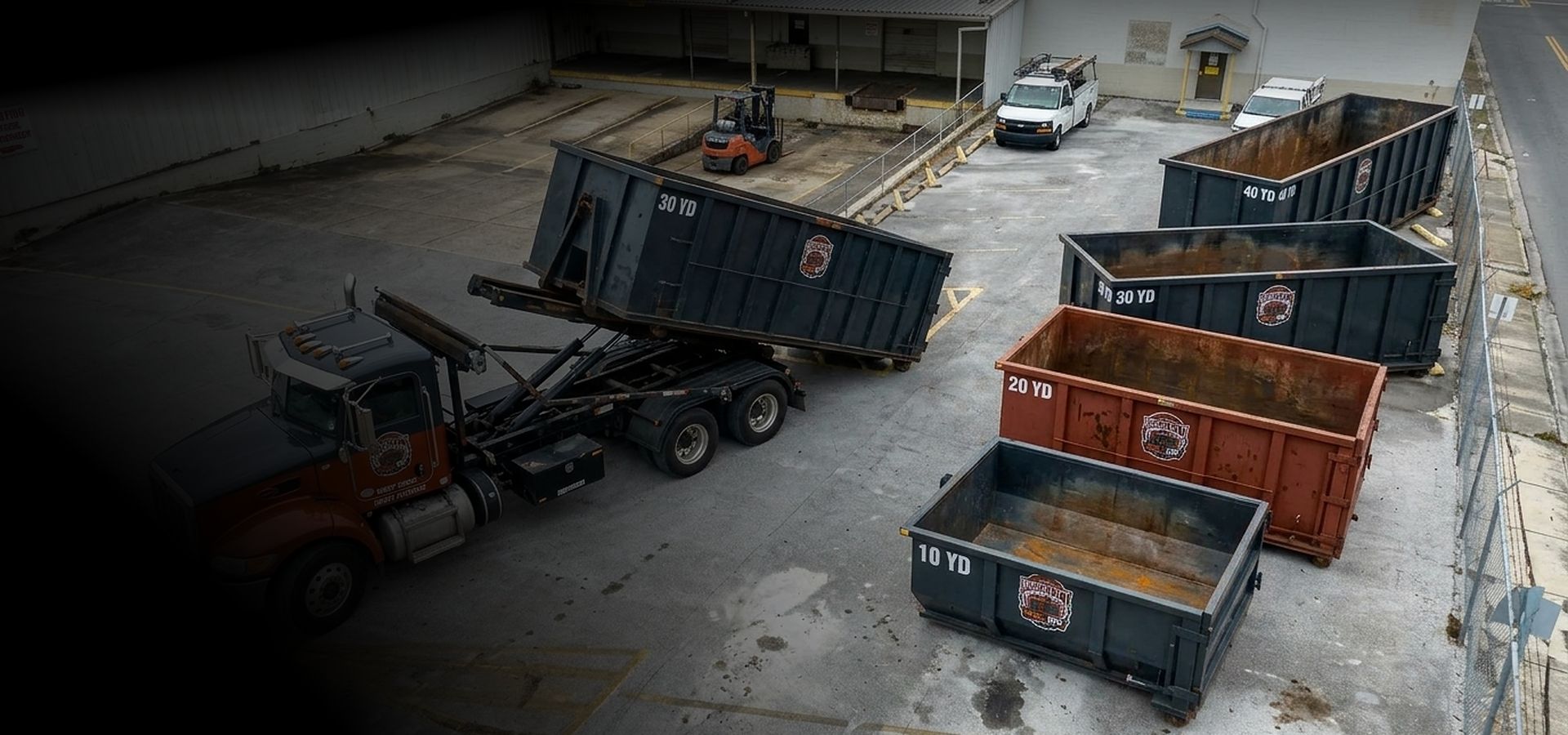 A BrickCity Roll Off truck with 10, 20, 30 and 40-yard roll-off containers in the company yard